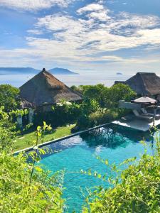a resort swimming pool with a view of the ocean at Bloo Lagoon Village in Padangbai