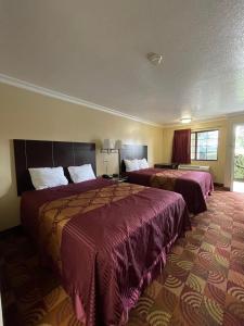 een hotelkamer met 2 bedden en paarse dekens bij Chino Motel in Chino
