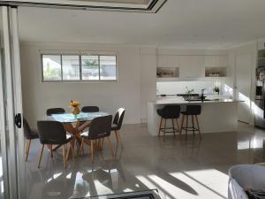 a kitchen with a table, chairs and a refrigerator at White Shells Luxury Apartments in Marcoola