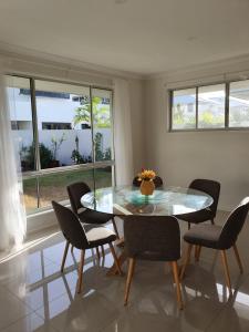 a dining room table with chairs and a window at White Shells Luxury Apartments in Marcoola