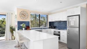 a kitchen with white cabinets and a large clock on the wall at Karinya at Little Beach Upstairs in Nelson Bay