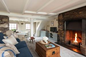 a living room with a large stone fireplace with a tv at Swallow Cottage in Port Isaac