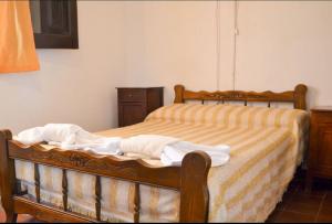 1 dormitorio con cama de madera con sábanas blancas y amarillas en Nuevo Hotel Agüero en Mina Clavero