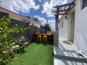 a small backyard with green grass and a fence at Walmer Cottage - Cute & Pet friendly in Cape Town