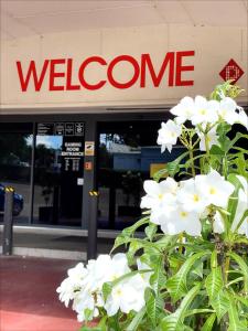 ein Gebäude mit einem Willkommensschild und weißen Blumen in der Unterkunft Inala Hotel in Brisbane