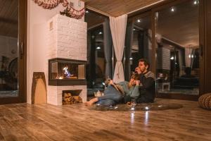 a man and a woman sitting on the floor in front of a fireplace at Skalny Zakątek z Grotą Solną na wyłączność in Łapsze Niżne