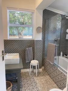 a bathroom with a sink and a shower and a stool at Walmer Cottage - Cute & Pet friendly in Cape Town +30 photos