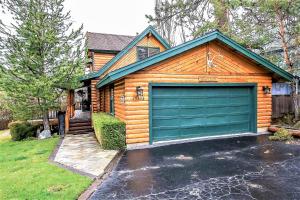 a wooden house with a green garage door at Knotty and Nice-177 by Big Bear Vacations in Big Bear Lake