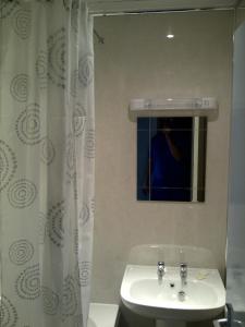 Baño blanco con lavabo y espejo en Lavender Cottage with Parking and Beautiful Views en Carsphairn