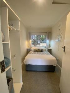 um pequeno quarto com uma cama e uma janela em Walmer Cottage - Cute & Pet friendly em Cidade do Cabo