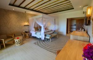 a bedroom with a bed and a couch and a table at Neptune Pwani Beach Resort & Spa Zanzibar - All Inclusive in Pwani Mchangani