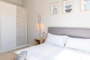 una camera da letto con un letto con lenzuola bianche e una finestra di Espectacular El Pilar8 By VigoVacaciones a Vigo
