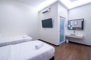 a room with two beds and a sink and a tv at King's Lane Ipoh in Ipoh