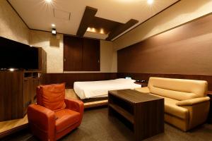 a room with a bed and a chair and a tv at 隠家（ajito）HOTEL555 小田原店 in Kami-soga