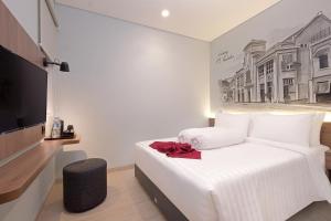 1 dormitorio con 1 cama blanca y TV en Azana Style Hotel Bandara Jakarta en Tangerang