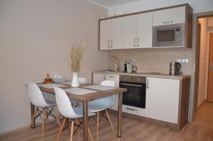 uma cozinha com uma mesa de madeira e cadeiras brancas em Apartmán Loučná - Špičákovi em Loučná nad Desnou