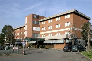 un gran edificio con coches estacionados frente a él en CDH Hotel Modena en Modena