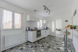 una cucina con armadietti bianchi e pavimento piastrellato di Le Vexin a Gisors