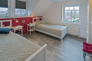 Un dormitorio con dos camas y dos ventanas. en Leuchtturm, en Dornumergrode