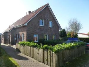 una casa de ladrillo con una valla delante en Leuchtturm, en Dornumergrode