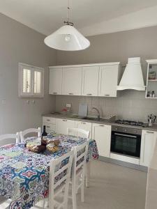 a kitchen with a table and white cabinets and a table and chairs at Villa Maria in Villanova di Ostuni