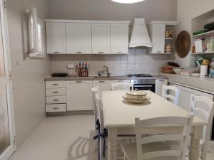 una cucina con armadi bianchi, tavolo e sedie di Villa Maria a Villanova