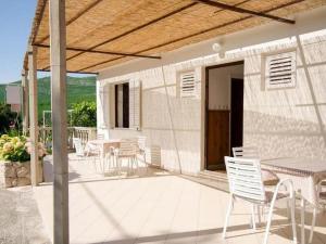 a patio with white chairs and tables and a building at Guest House Rooms Rose in Molunat