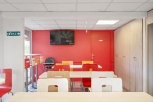 comedor con paredes rojas, mesas y sillas en Premiere Classe Lyon Est - Bron Eurexpo, en Décines-Charpieu