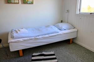 a small bed in a room with a window at The Little Red Cabin Near Blåvand! in Blåvand