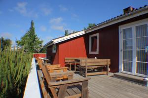 una terrazza con panche, tavolo e edificio di The Little Red Cabin Near Blåvand! a Blåvand