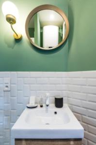 La salle de bains est pourvue d'un lavabo blanc et d'un miroir. dans l'établissement CMG Cosy Studio- 2P - Nation - Voltaire, à Paris