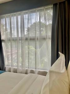 a bedroom with a bed and a window with white curtains at Bravo Tanauan Hotel in Tanauan