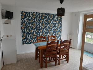 uma sala de jantar com uma mesa e cadeiras e um quadro em location appartement 100 m de la plage em Pénestin