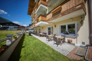 an outdoor patio with tables and chairs and a lawn at Hotel Schachner in Saalbach-Hinterglemm
