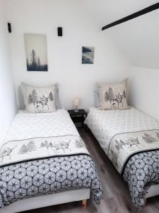 two beds in a room with white walls at Gîte L'Equilibre - Lac/montagnes- Familles-groupes in Kruth