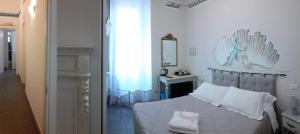 a white bedroom with a bed and a mirror at L'Angelo Blu in La Spezia