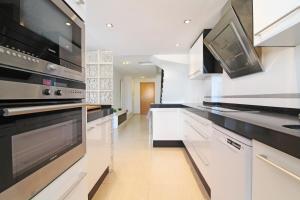 una cucina con armadietti bianchi ed elettrodomestici neri di Global Properties, Impresionante ático para 8 personas en Canet d'en Berenguer a Canet de Berenguer