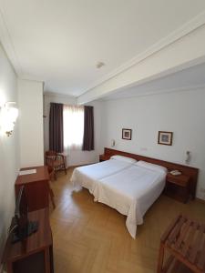 Schlafzimmer mit einem großen weißen Bett und Holzböden in der Unterkunft Hotel ELE Acueducto in Segovia