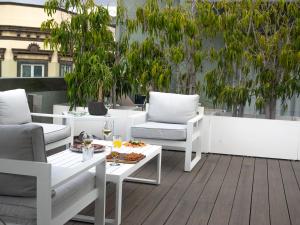 un patio con muebles blancos, mesa y sillas en Suites 1478, en Las Palmas de Gran Canaria