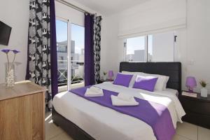 een slaapkamer met een groot bed met paarse en witte kussens bij Villa Nissinia - Nissi Beach Area in Ayia Napa +25 foto's