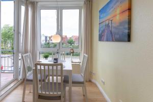 een eetkamer met een tafel, stoelen en ramen bij Knechtsand 426 in Cuxhaven
