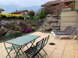 a patio with a table and chairs and flowers at Haut de Cry in Conthey