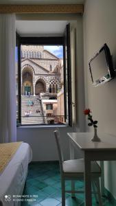 
a hotel room with a bed, table and window at Albergo S. Andrea in Amalfi
