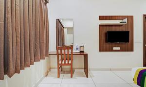 a room with a chair and a table and a television at Treebo Trend RJ Residency in Mysore
