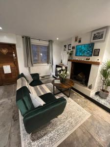 a living room with a green couch and a fireplace at Bay Cottage, Hot Tub in Snitterfield