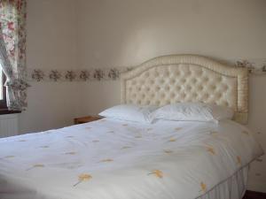 a bed with a white bedspread and pillows on it at Lavender Cottage with Parking and Beautiful Views in Carsphairn
