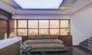 a living room with a couch and a large window at Treebo Trend RJ Residency in Mysore
