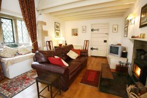a living room with a leather couch and a tv at Welsh Gatehouse in Mathern