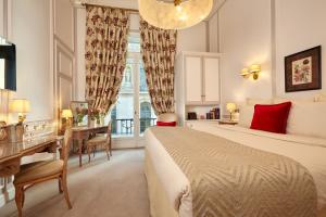 パリにあるオテル レジーナ ルーブルのベッド、デスク、窓が備わるホテルルームです。