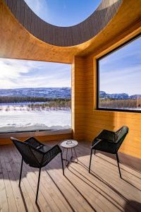 a room with two chairs and a table and a large window at Sorrisniva Arctic Wilderness Lodge in Alta